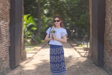 Pretty Asian tourists woman wearing beautiful hand-woven clothes dyed with indigo and mud-fermented natural colors modern Thai traditional dress costumes are popular in ancient temple Thailand.