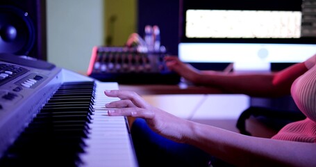 Woman hands on keyboard of piano. Musician woman hands playing piano in studio and purple neon...