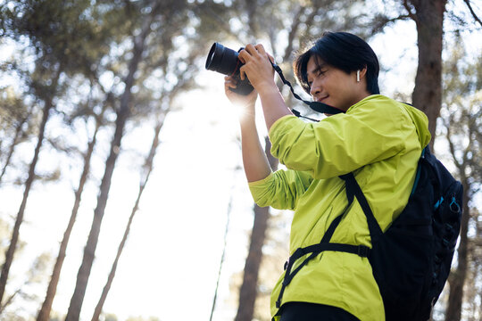 A Korean man is hiking in the middle of Mt. The boy is taking a picture with a digital camera of the species of the mountain. Concept of bird photography, photographing species outdoors.