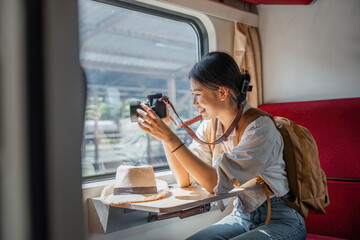 Beautiful Asian female tourist with sitting and take a photo travel location and sightseeing urban window view, public train transport, city lifestyle journey by railway - obrazy, fototapety, plakaty