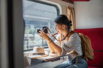 Foto op Canvas Beautiful Asian female tourist with sitting and take a photo travel location and sightseeing urban window view, public train transport, city lifestyle journey by railway © Natee Meepian