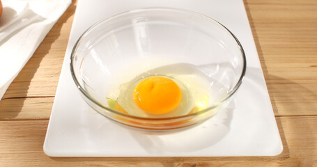 Cracked eggs. Raw egg pours into bowl. Breakfast preparation. Rustic style. Sunny day. Smooth camera movement. Close up. 4k footage.