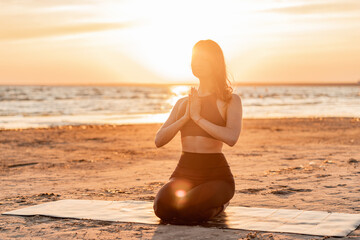 The trainer uses an aerobics mat at sunset. Balance and meditation woman training yoga asana...