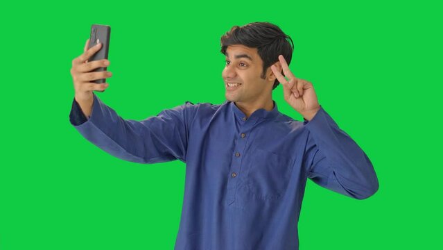 Happy Indian man clicking selfies Green screen
