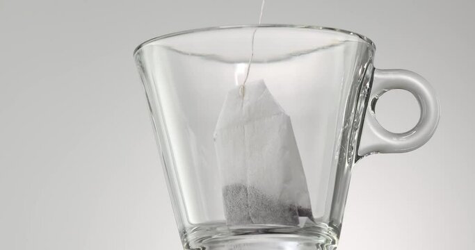 tea brewing. a tea bag is dropped into an empty transparent mug. High quality 4k footage