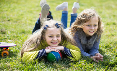 two blonde girl lie on grass in spring