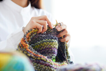 リビングにて趣味の手芸で毛糸を編む30代の日本人女性