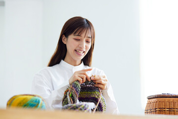 リビングにて趣味の手芸で毛糸を編む30代の日本人女性