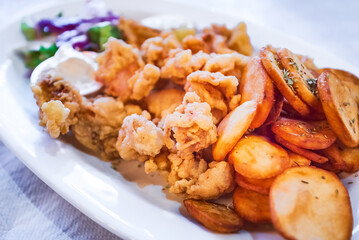 Classic greek taverna plate with fried calamari and baked potatoes, seafood.