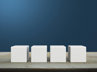 Four white block cubes on wooden table over light blue wall