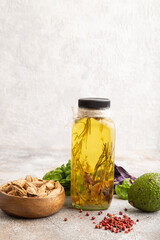 Sunflower oil in a glass jar with various herbs and spices on a brown concrete. Side view, copy space.