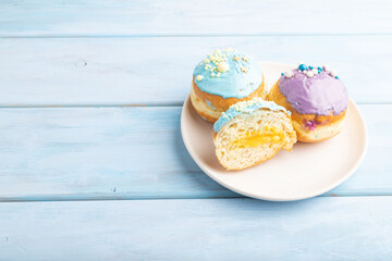 Purple and blue glazed donut on blue wooden, side view, copy space.