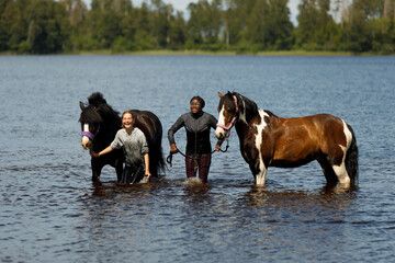Girls with horses standing in river