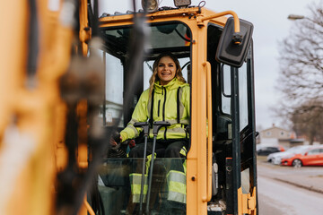 Portrait of smiling female road worker operating excavator