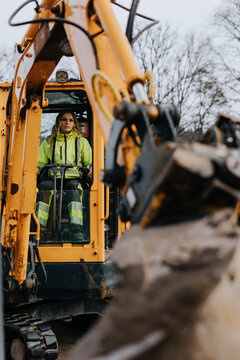 Female road worker operating excavator