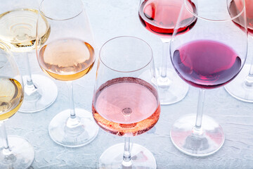 Wine glasses at a tasting. Rose, red, and white wine, drinks on a table at a winery. An assortment of wines of many different colors, sommelier event