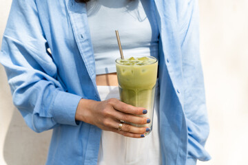 Female drinking Iced matcha latte in the summer city. Healthy detox diet