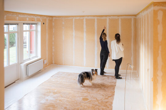 Female painter priming room for painting