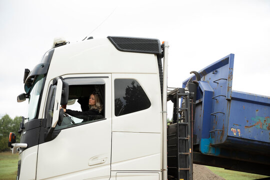 Woman driving long-distance lorry preparing to tipping off the load