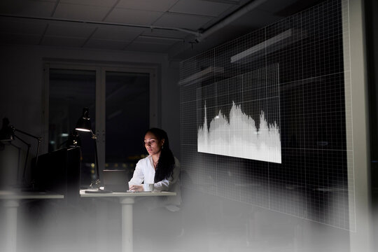 Female finance specialist working in office at night