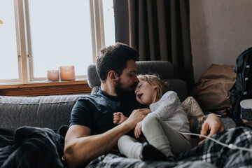 Father hugging disabled child on sofa