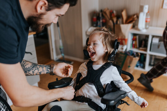 Father taking care of happy disabled child in wheelchair