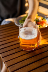 Holding glass with apple cider at dinner table. Fresh and iced apple drink