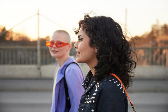 Side view of smiling young woman, female friend in background