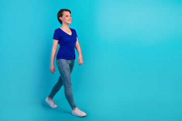 Fototapeta na wymiar Full length profile photo of girl walking smiling isolated on bright blue color background