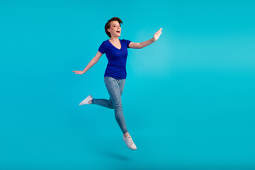 Fototapeta na wymiar Full length charming cheerful girl jumping having fun isolated blue turquoise color background