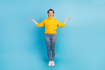 Photo of attractive lady good mood hold hands demonstrate two novelty products wear casual sweater jeans isolated blue color background