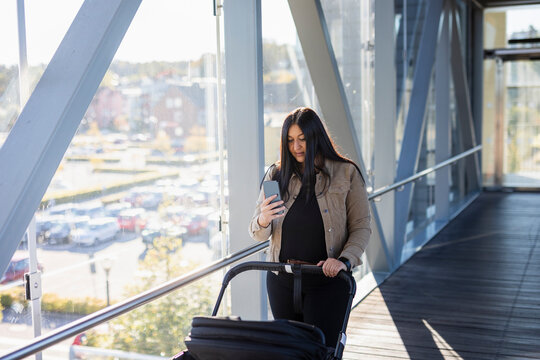 woman on parental leave with pram using cell phone to photograph