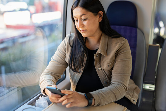 Mid adult woman in train using cell phone