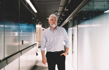 Senior man standing in corridor of modern building