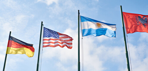 Germany, USA, Albania and Argentina flags on sky