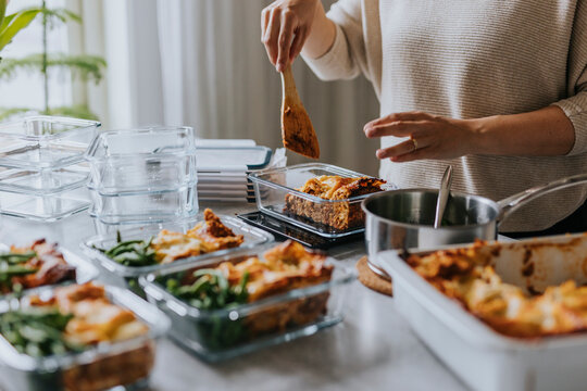 Woman weighing lunch boxes as part of healthy meal prep