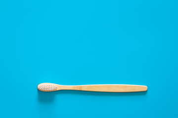 Natural eco-friendly bamboo brush on a blue background, copy space.