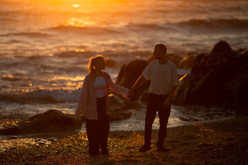 A golden sunset and a young couple having fun on the beach.