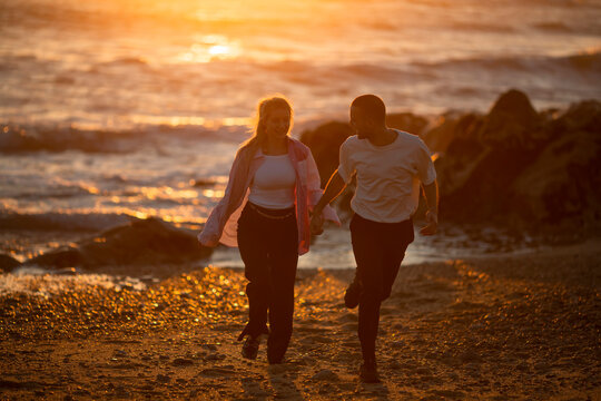 A young couple enjoying a golden sunset on the beach.