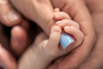 The small hand of a newborn holds the mother's finger.