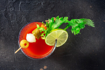 Bloody Mary cocktail with garnish on a black slate background, top shot. Spicy tomato juice with alcohol, lime, pickles, and celery, with ice © CookShootsFood