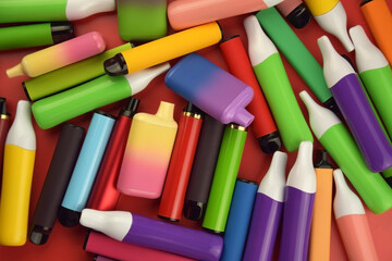 Set of multicolor disposable electronic cigarettes on a red background.