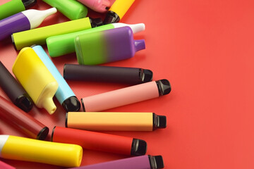 Set of multicolor disposable electronic cigarettes on a red background. - obrazy, fototapety, plakaty