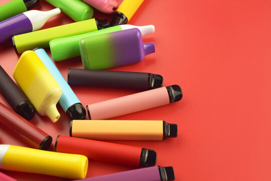 Set of multicolor disposable electronic cigarettes on a red background.