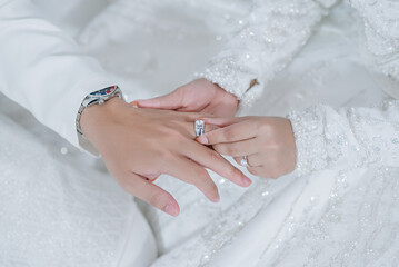 malay wedding bride bolstering ring on groom's finger. Bride wear wedding rings to left finger of groom, Muslim wedding, Wedding Poster, Close up hand.