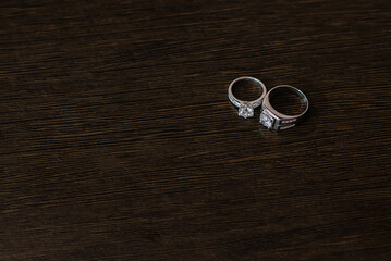 Wedding rings on a dark brown wood grain background. A couple's diamond ring against a wooden background.