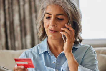 Close Up Of Mature Woman At Home Giving Credit Card Details On Mobile Phone