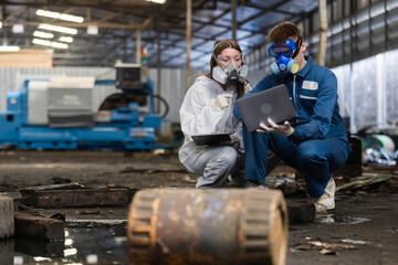 Team inspector chemical and hazmat wearing protective mask using laptop and write note on clipboard. Wastewater chemical residue in factory. Analysing harmful substances to human body environment.