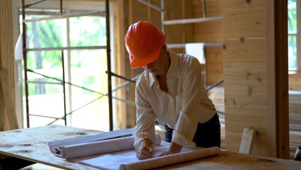 Woman architect reviewing blueprints and checking drawings in a new home construction project inspection.