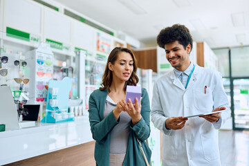 Obraz premium Young woman buying medicine with help of pharmacist in drugstore.